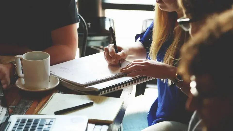 A business meeting with notebooks and pens on a table