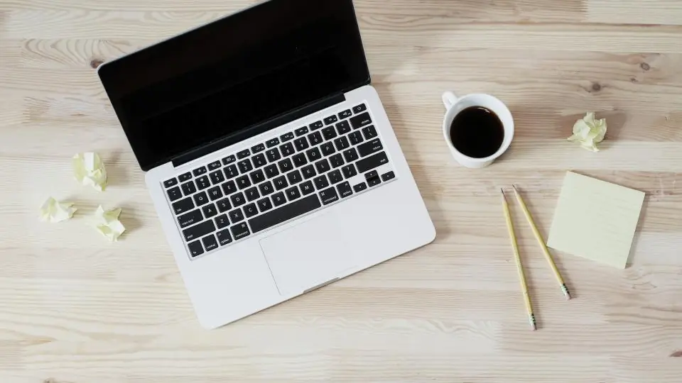 A laptop and coffee on a desk with an email inbox on screen