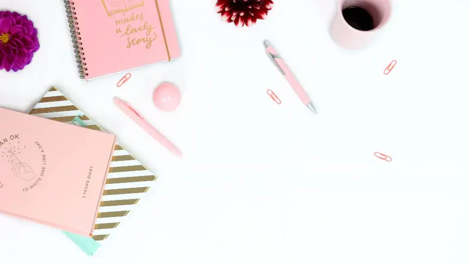A tidy desk with notebooks, pens and paper clips
